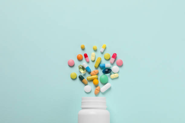istock Plastic bottle with many different pills on light blue background, flat lay 1875213548