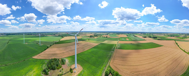 Aerial view of powerful Wind turbine farm for energy production on beautiful cloudy sky at highland. Wind power turbines generating clean renewable energy for sustainable development.