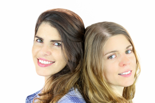 Portrait of smiling female friends hugging on white background