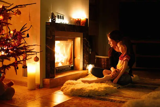 Young mother and her daughter by a fireplace on Christmas