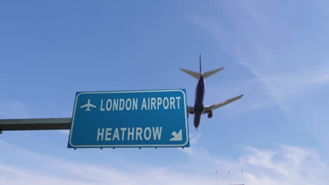 airplane passing over heathrow airport road sign