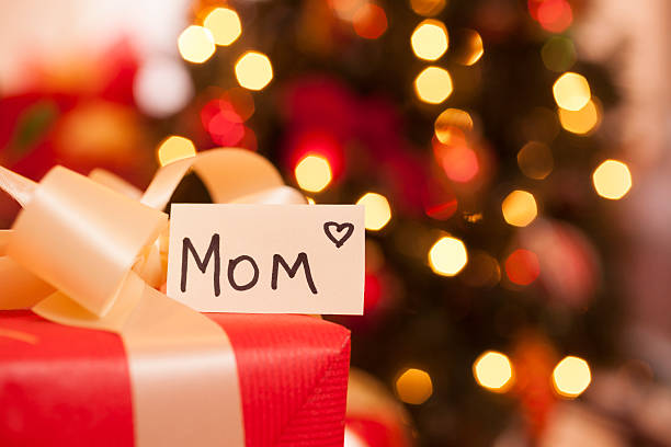 istock Christmas:  Holiday gift for Mom. Lit tree in background. 187529579