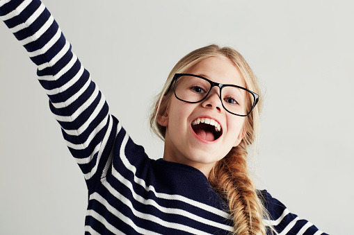 Portrait of amazed cute little girl with pigtails in white t-shirt on white studio background