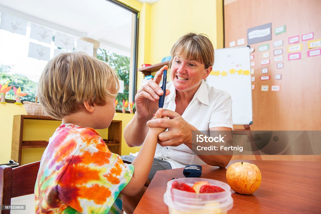 Testing blood sugar at school A nurse shows a diabetic child how to test his blood. in a classroom in school. Education Stock Photo