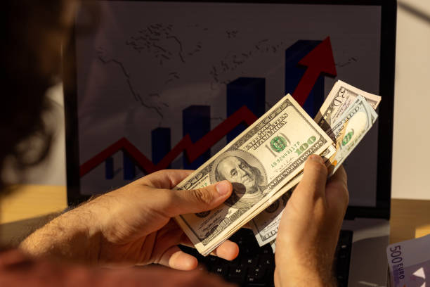 Unrecognizable male entrepreneur counting dollars An over-the-shoulder view of an unrecognizable young Caucasian male entrepreneur/freelancer counting US paper currency Profits Look Good but Cash Feels Tight stock pictures, royalty-free photos & images