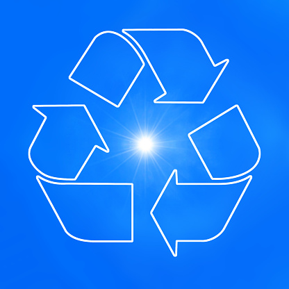 The universal recycling symbol. It is an internationally recognized symbol for recycling. Against blue sky and with the sun.