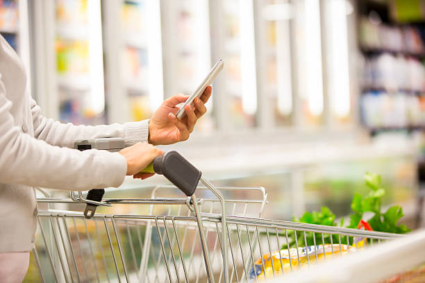 Close-up of woman with trolley and smartphone stock photo