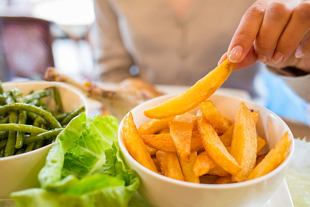 Woman eats French Fries at restaurant, salad, vegetable stock photo