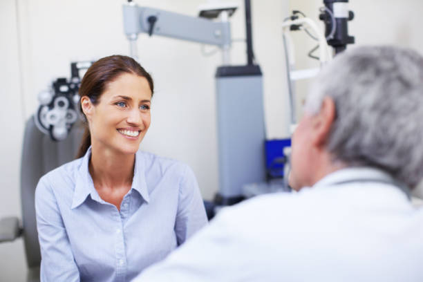 Helping her understand the need for an eye examination A mature optometrist talking to a patient eye test equipment stock pictures, royalty-free photos & images