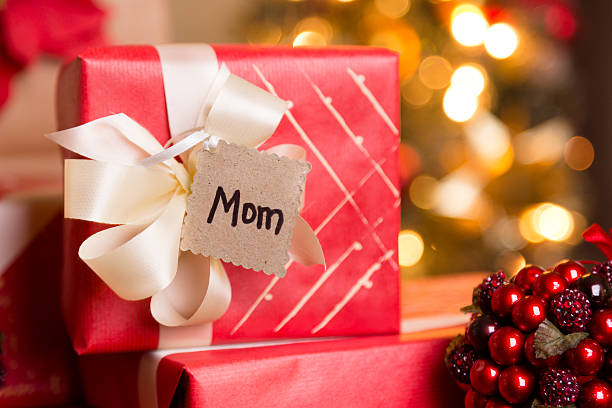 istock Christmas:  Beautifully wrapped holiday gift for Mom. Tree in background. 187536426