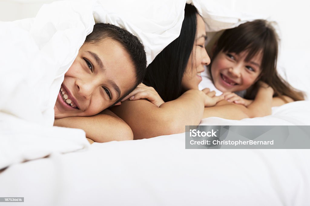 Madre e hijos sentar en la cama - Foto de stock de Niñas libre de derechos