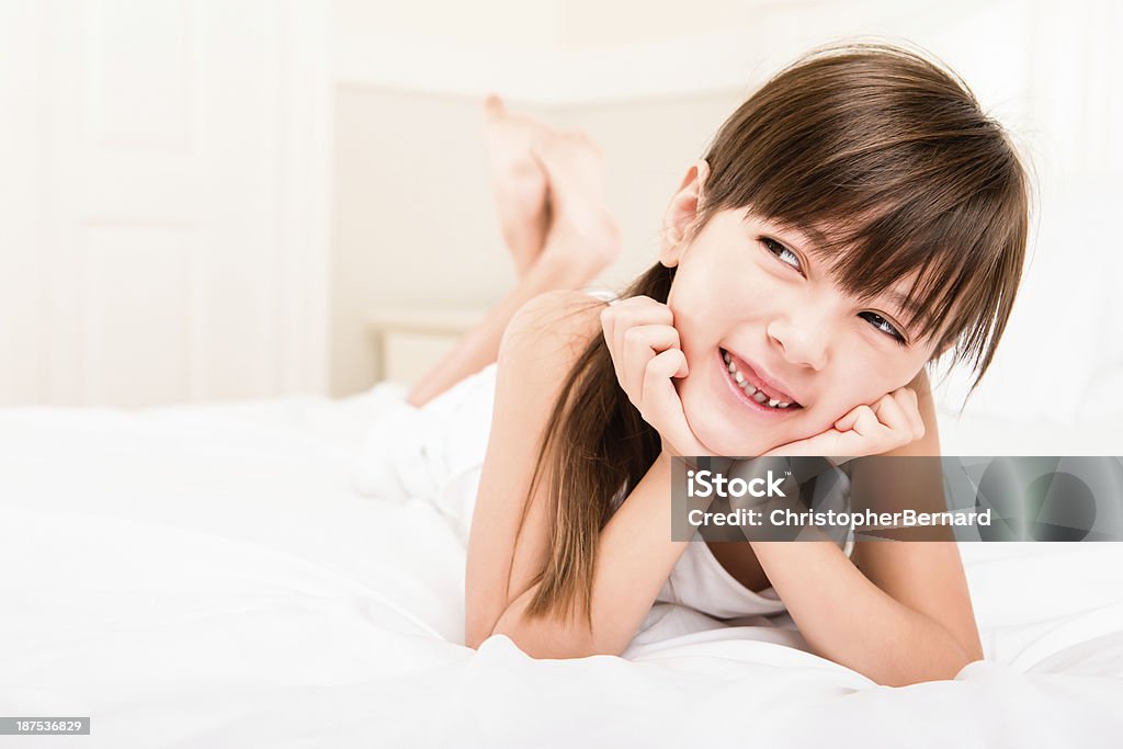 Sorridente garota jovem colocar na cama - Foto de stock de Menina royalty-free