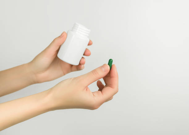 istock female hands holding a green pill and a white pill bottle 1875376601