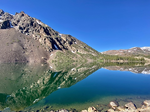 ellerly lake reflects the surrounding hillsides like a mirror within yosemite national park.