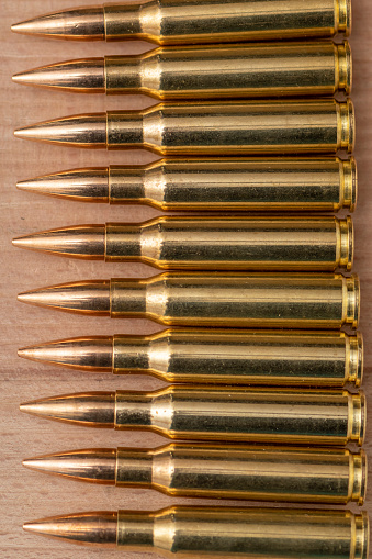 A row of cartridges with 7.62 caliber bullets for a Kalashnikov assault rifle on a textured background, close-up, selective focusing. Concept: sale of weapons under lend-lease, assistance with weapons