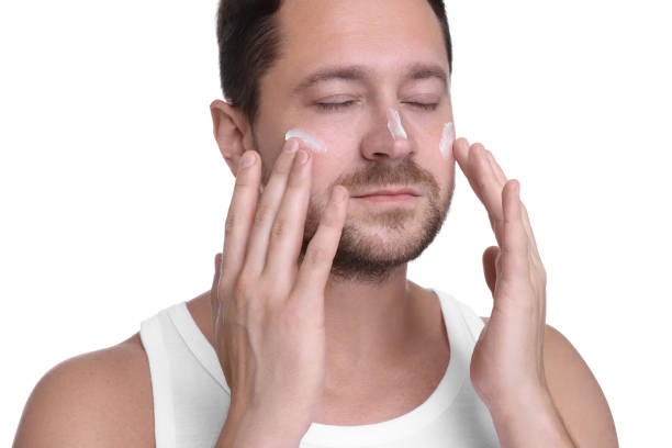 istock Man applying sun protection cream onto his face against white background 1875414854