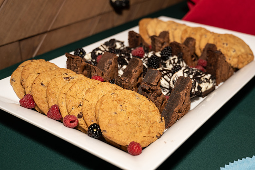 Finger food for the party guests to eat consists of brownies and chocolate chip cookies on a platter.