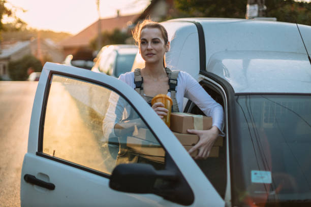 istock Young woman driving a white van and delivering packages 1875454355