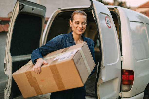 istock Young woman unloading the van and delivering packages 1875456949