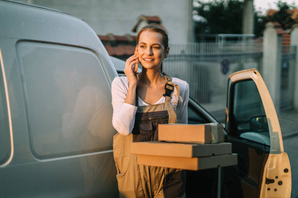 istock Smiling woman talking on a phone and delivering packages 1875457990