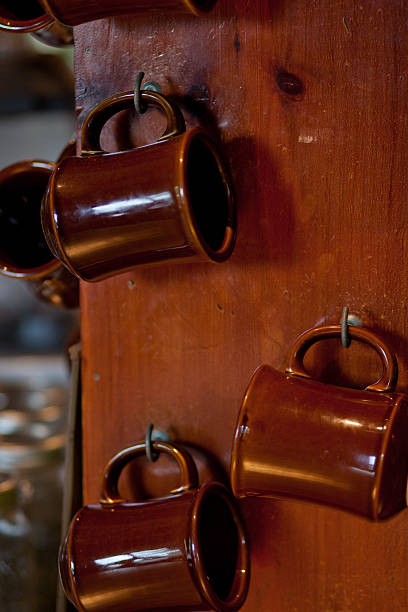 coffee mugs hanging on wood pillar - vertical stock photo