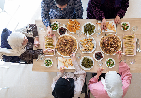 Top view for Arabian family having dinner together on wooden table with father,mother,grandfather,grandmother and son