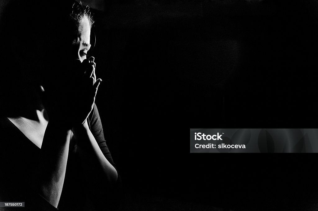 Woman in shadows crying on black Young woman stanging in the dark crying,she is feeling hopless . Women Stock Photo