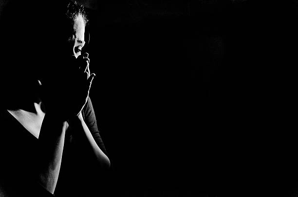 Woman in shadows crying on black Young woman stanging in the dark crying,she is feeling hopless . women crying stock pictures, royalty-free photos & images