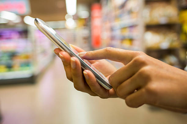 istock Smartphone and hands with supermarket background 187550369