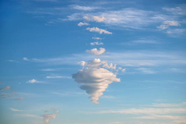 Strange cloud shaped like a cone. Blue sky with fluffy clouds. Abstract natural background