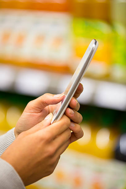 istock Woman using mobile phone while shopping in supermarket 187550983