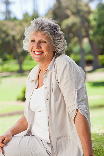 istock An elderly woman is smiling and sitting on the grass 187554246