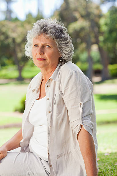 istock Elderly woman is sitting on the grass and thinking 187554267