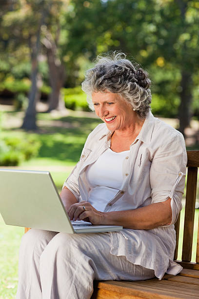 istock Smiling old woman typing on laptop 187554386