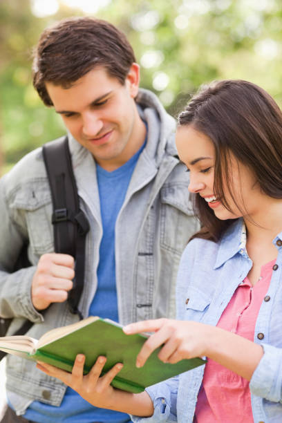 istock Female student laughing while showing a book to his buddy 187555470