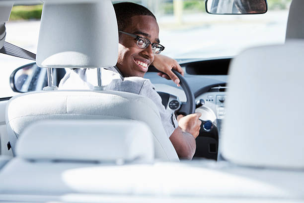 Young man driving car Young African American man (19 years) driving car. teenager boy driving stock pictures, royalty-free photos & images