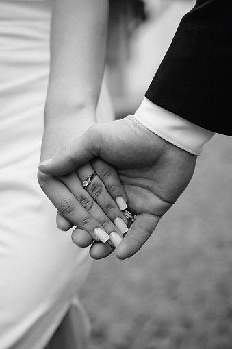 Young married couple holding hands, wedding day.Close up ,black and white photo,Golden,wedding rings