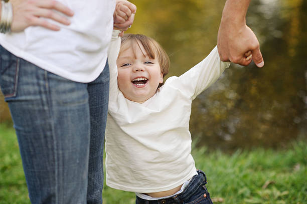istock Happy Boy Holding Parent's Hands 187559986