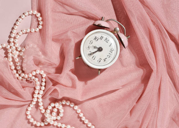 Vintage alarm clock and layers of pastel pink tulle, flat lay composition, elegance, femininity, retro nostalgia.