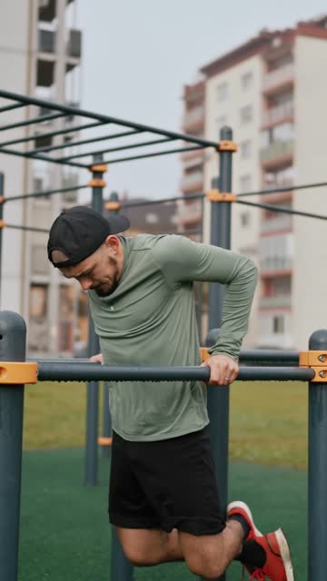 Young Man in Sportswear Doing Pull-Ups Exercise on Horizontal Bars in Park
