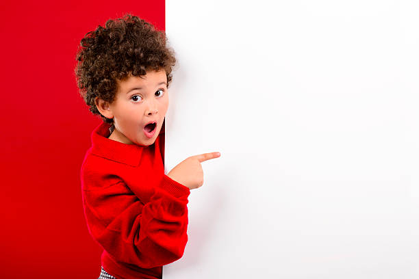 Happy child shows something on a white board stock photo