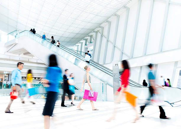 A high angle view looking down on a shopping mall walkway, two levels visible, people walking in both directions or just standing around.  Horizontal image.  Shot in Hong Kong.