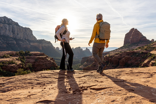 Mature couple pause on red rock path in desert landscape