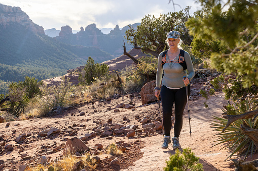 Mature woman hikes along red rock path in desert landscape