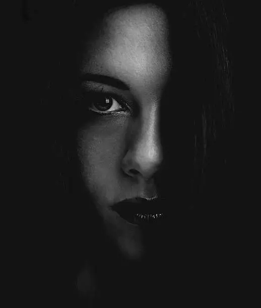 Cropped dark portrait of a young woman's face