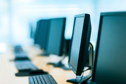 A row of computer monitors and keyboards.  