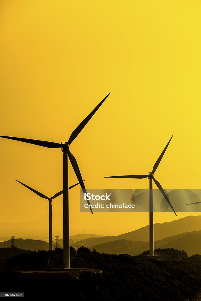 Torri elettriche e turbine eoliche al tramonto - Foto stock royalty-free di Alimentatore