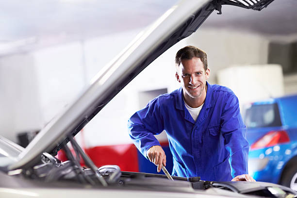 He's a brilliant mechanic! Portrait of a smiling car mechanic working on a car engine jumpsuit stock pictures, royalty-free photos & images