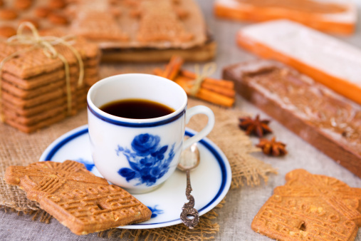 A cup of coffee with traditional Dutch 'speculaas' (spiced shortcrust cookies). Authentic wooden cookie cutters especially made for these cookies can be seen in the background.