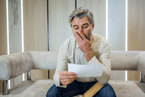 Stressed angry businessman opening envelope, reading banking credit loan refusal notification. Unhappy man received bad news, irritated by mistake, feeling stressed about dismissal notice.